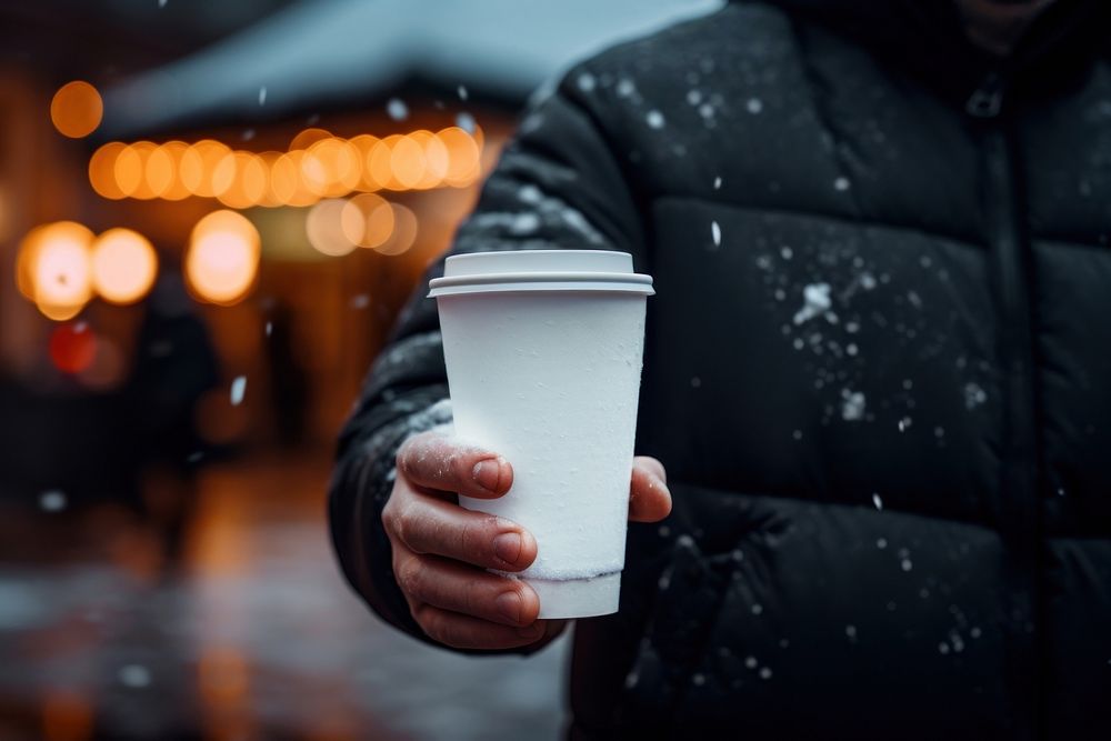 Man in a holding a coffee cup snow street drink.