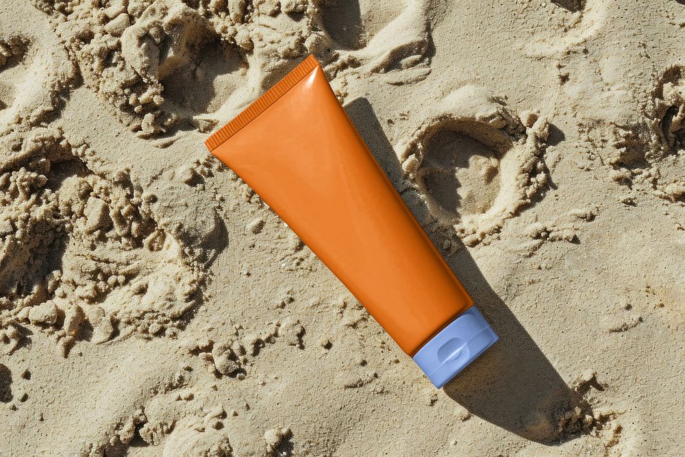 Orange sunscreen tube on a beach