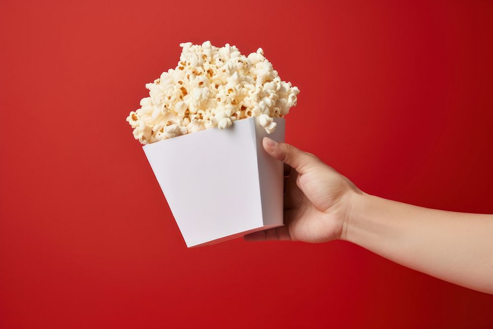 Hand holding popcorn snack paper food.