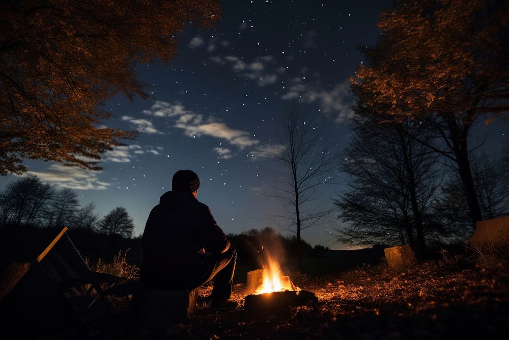 Young alone camping in autumn night fire outdoors.