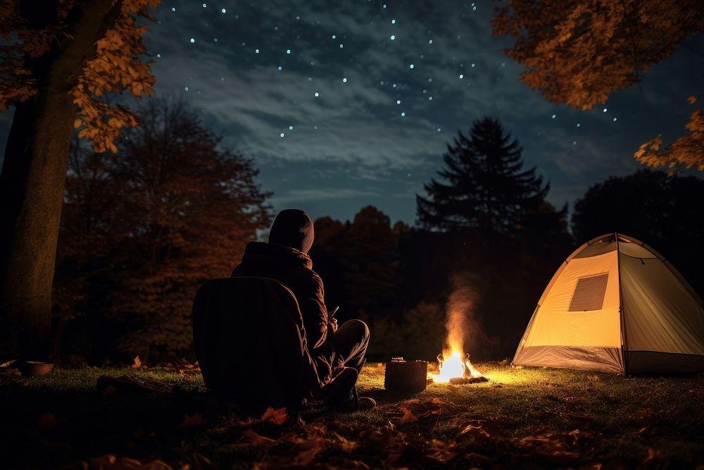 Young alone people and their pets camping in autumn night fire outdoors.