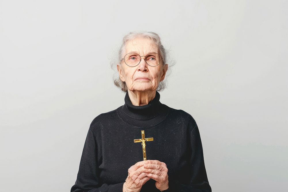 Senior woman holding gold cross portrait sweater white background.