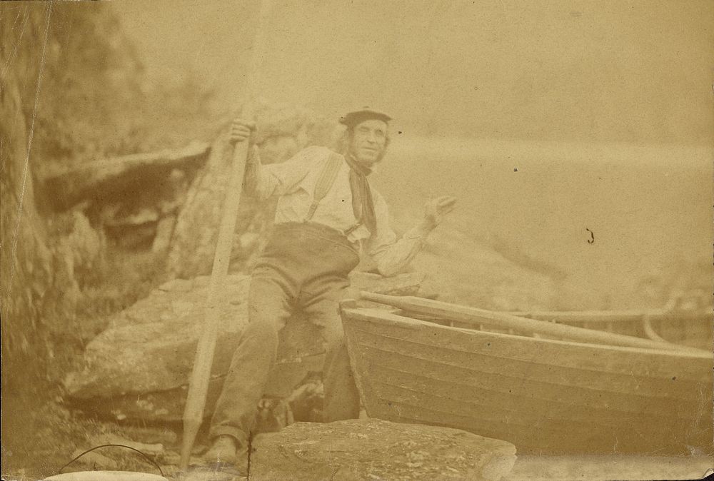 Man posing beside rowboat