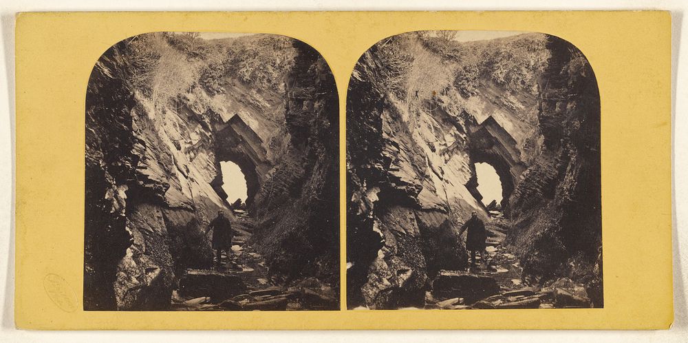 Man standing within jagged rocks, hole at center by Britton