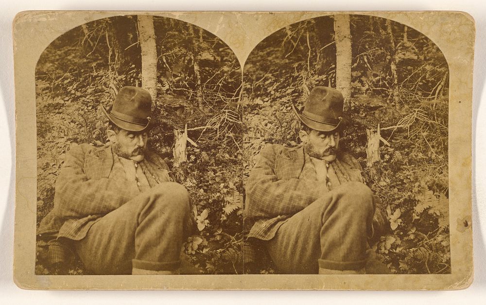 Man with moustache and long sideburns wearing a hat sleeping under a tree in the woods, probably in New Hampshire by…