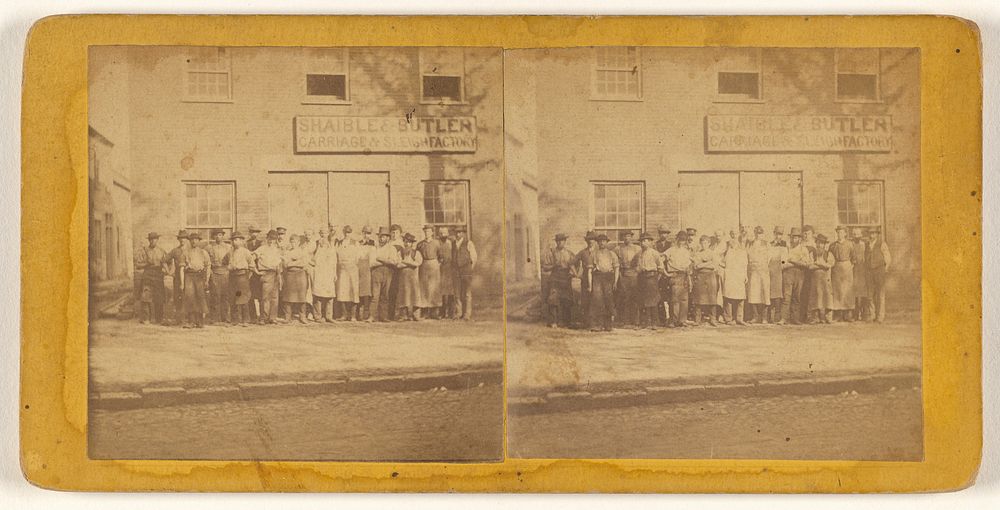 Group of people posed in front of building of Shaible & Butler Carriage & Sleigh Factory