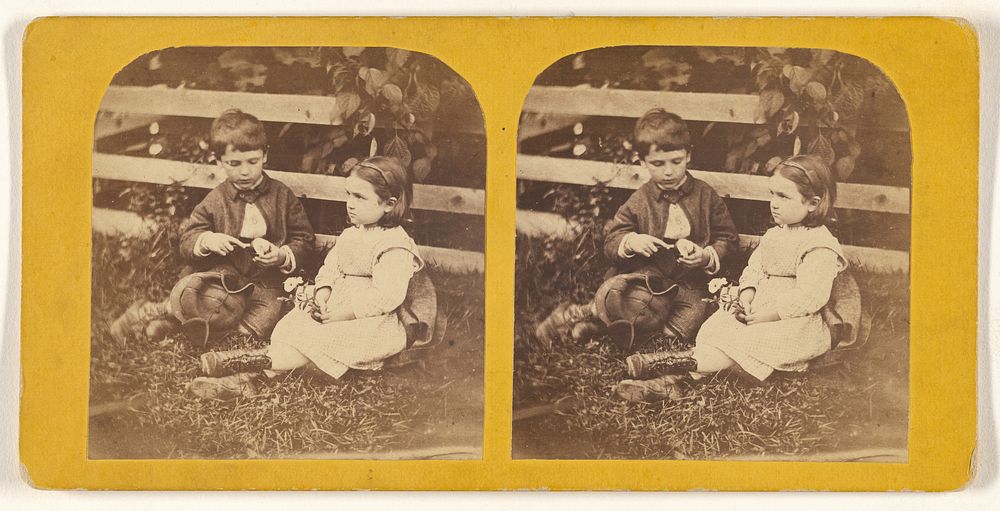 Little boy and girl posed on grass near fence