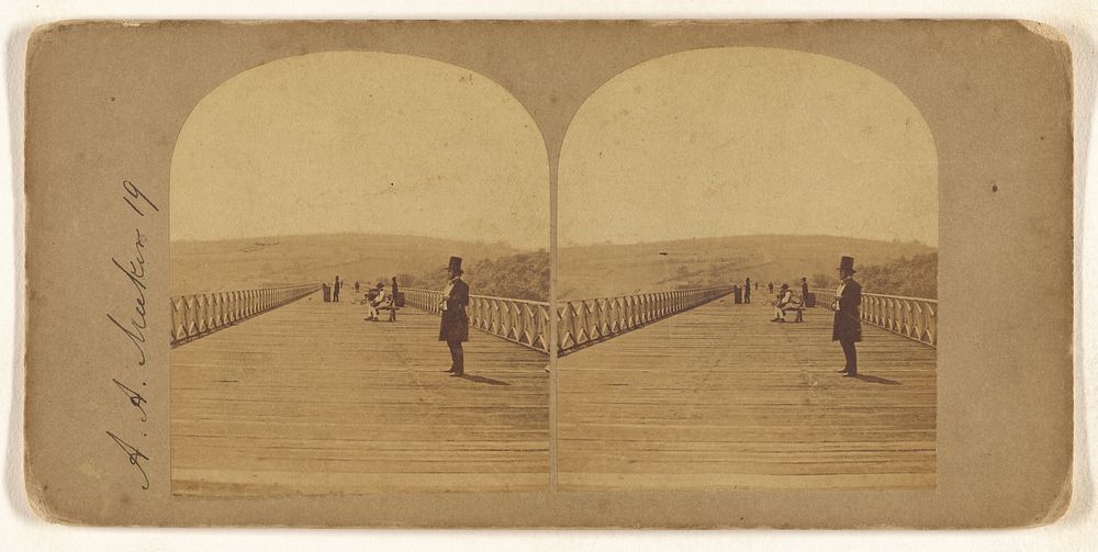 Man with top hat standing on long wooden bridge