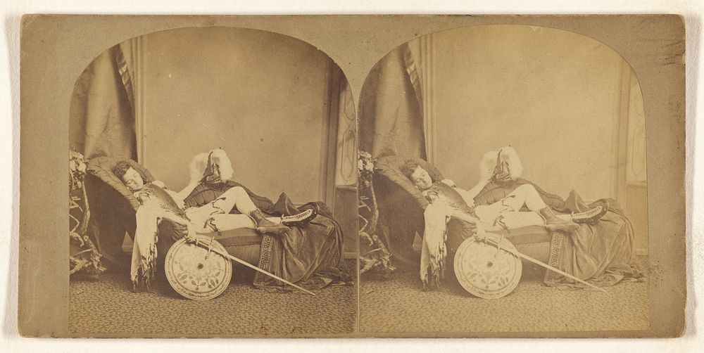 Young soldier asleep on a couch, helmet, sword, and shield in hands