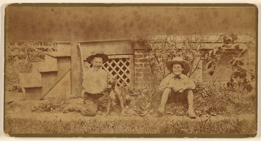 Two boys seated on ground with a dog