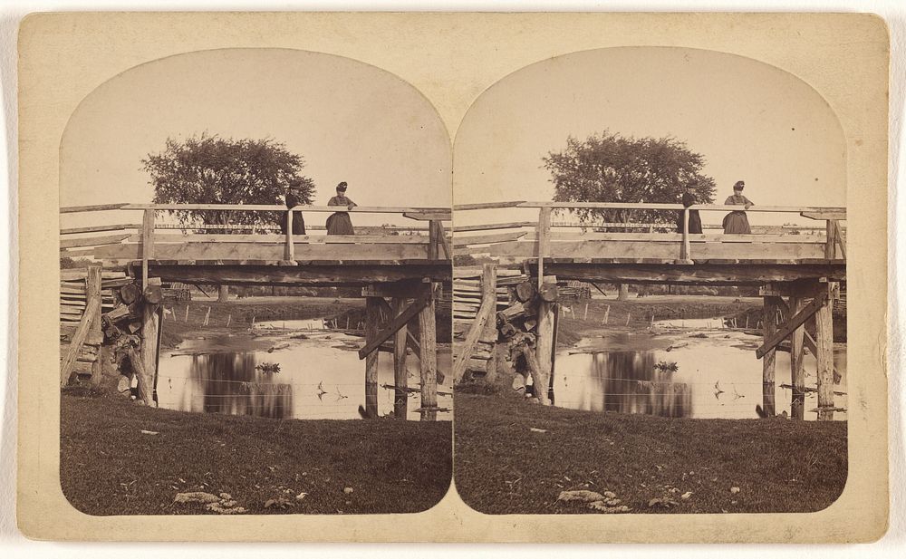Two women standing on a wooden bridge, shallow stream underneath by Ottomar Tarecki