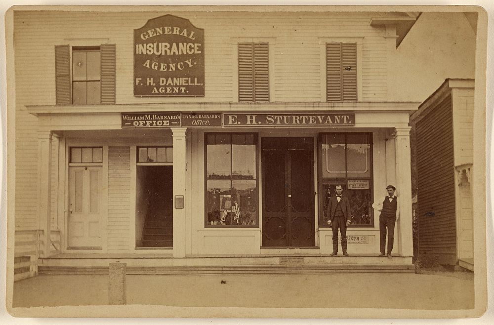 Two men posing in front of offices of M. Barnard, Daniel Barnard, E.H. Sturtevant & General Insurance Agency by S P Brown
