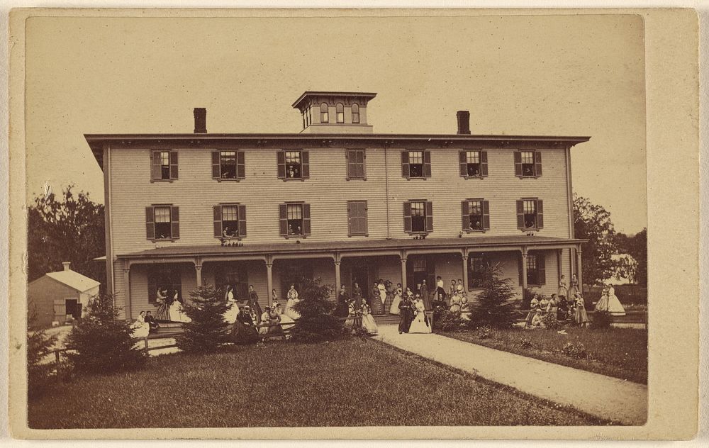 View of a house with numerous people on porch and lawn by Yeaw and Company
