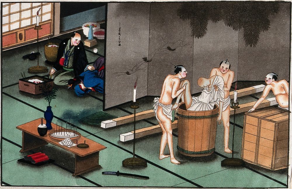 Japanese funeral customs: two attendants wearing loin-cloths place the body of a dead man in a round wooden vessel while a…