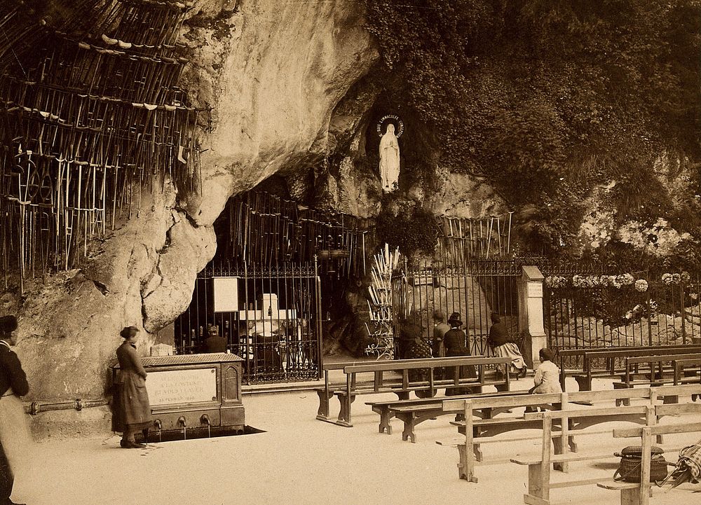 Lourdes, France: the Grotto of Our Lady of Lourdes: pilgrims at the shrine; the sacred water fountain to one side.…