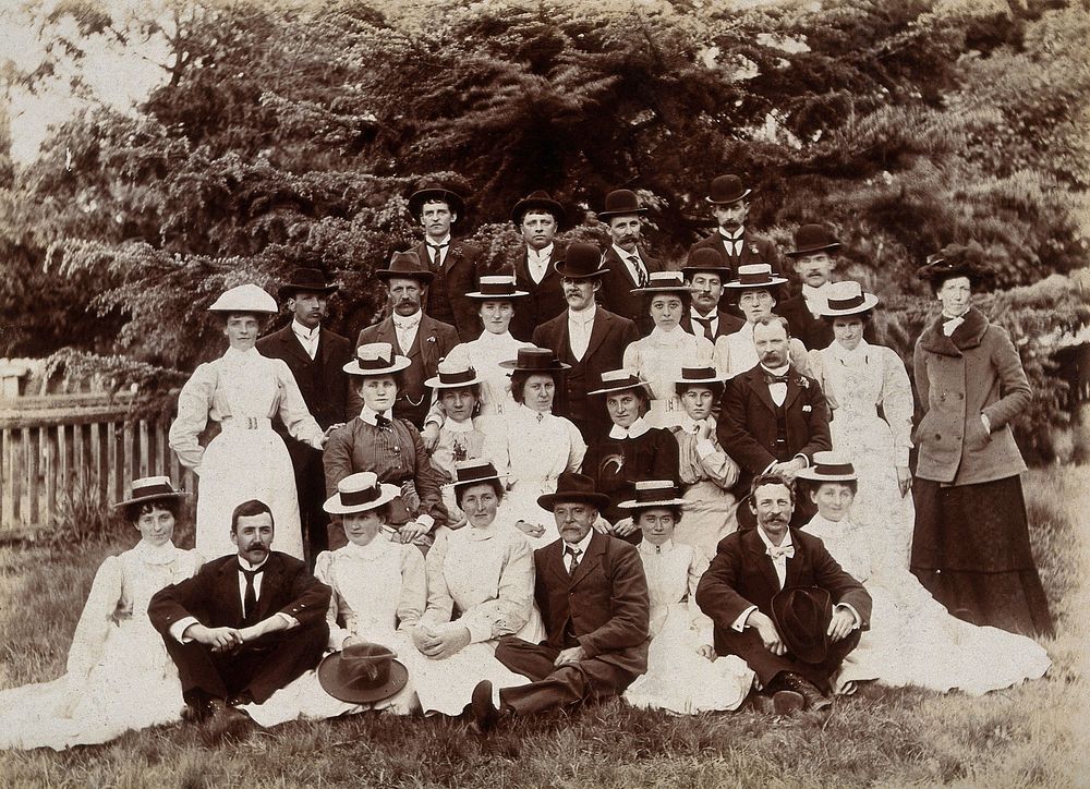 A group of hospital staff, including nurses wearing matching straw hats, standing outdoors. Photograph.