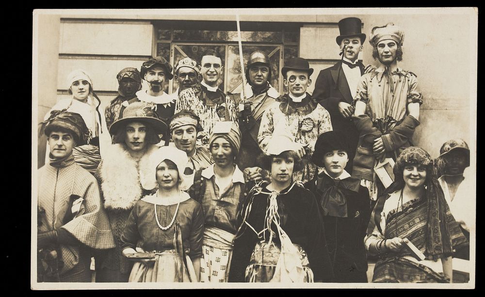 People gathered outside a building wearing various costumes, some in drag. Photographic postcard, 1924.