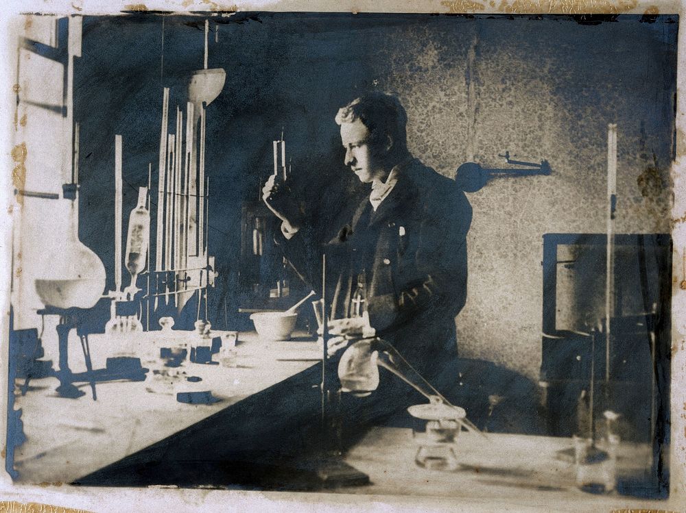 A young man conducting an experiment in a chemical laboratory. Photograph.