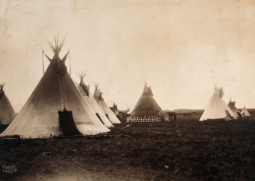 A Piegan encampment, North America: tipis, including a decorated medicine tipi (centre). Photograph by Edward S. Curtis…