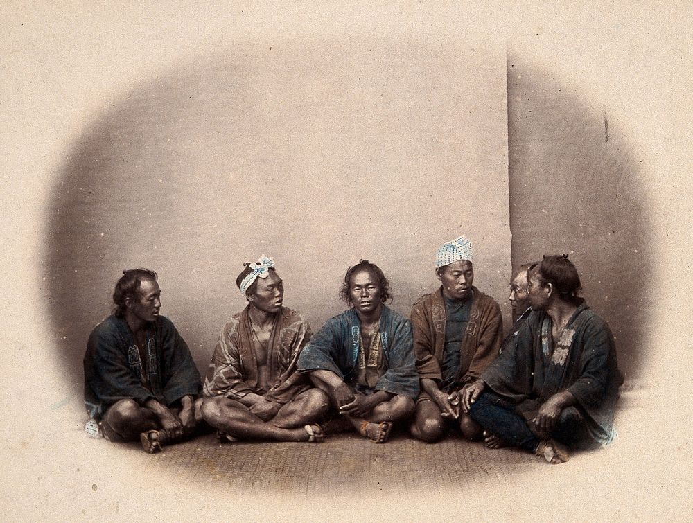 Japanese men sitting on the floor in a group. Coloured photograph by Felice Beato, ca. 1868.