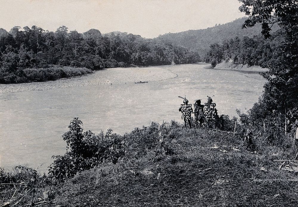 Sarawak: three men standing by the Baram River. Photograph.