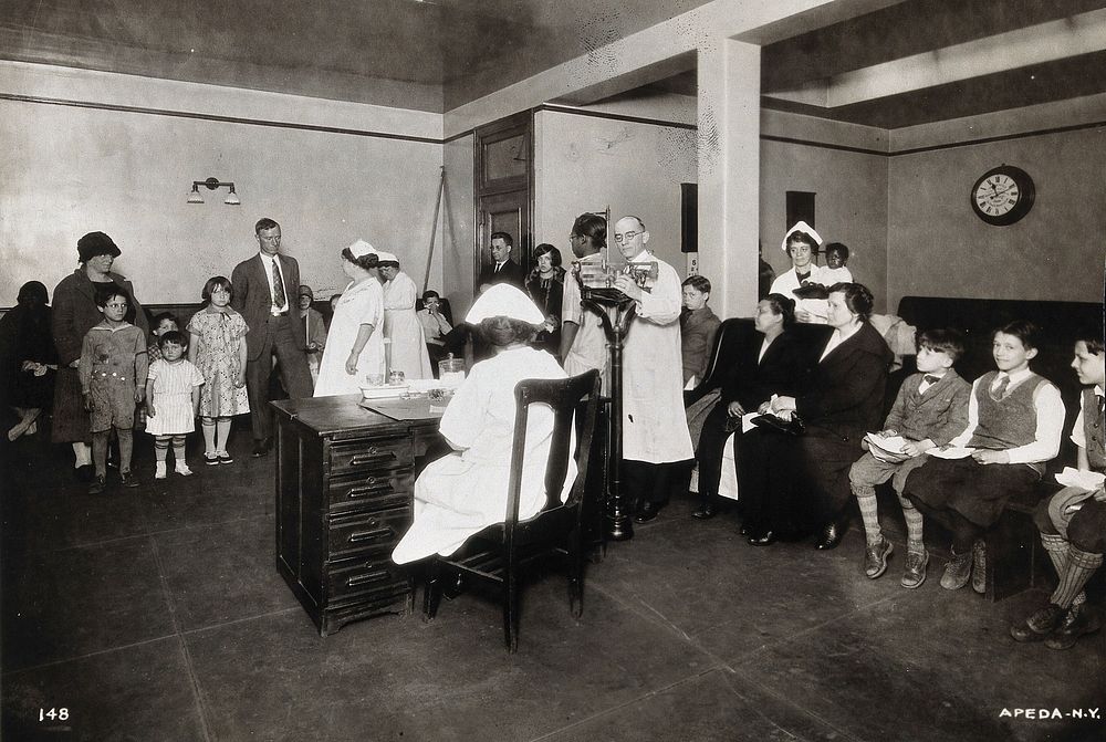 Interior of a state clinic, Pennsylvania: a nurse is shown seated at a desk, while doctor measures a girl's height and other…