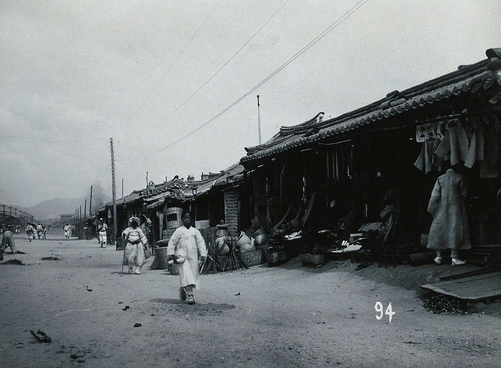 A line of shops beside a dusty street, with telegraph poles overhead, in Korea.