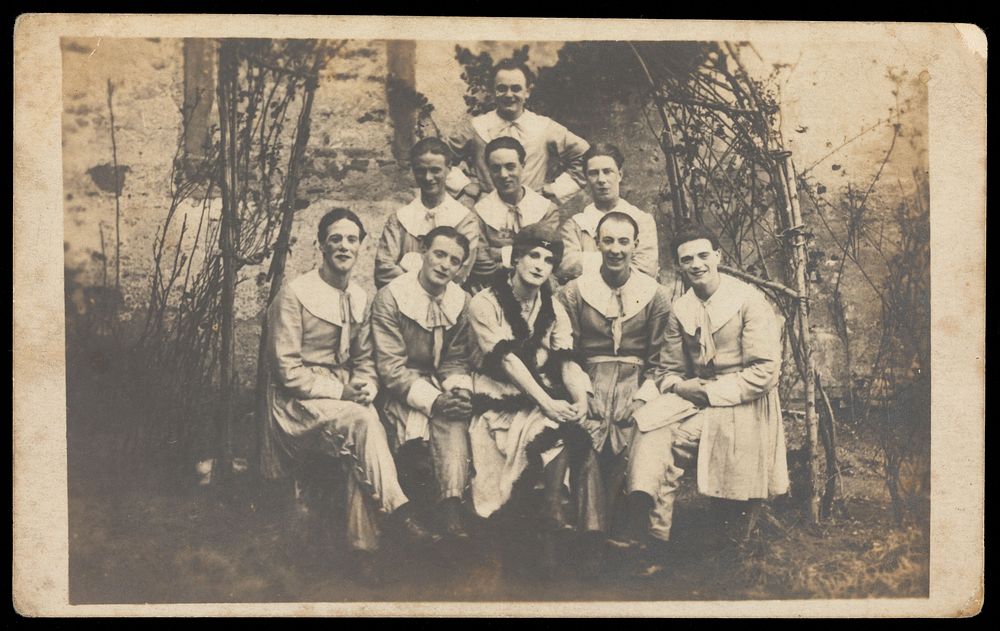 Concert party performers, one in drag, pose for a group portrait. Photographic postcard, 191-.