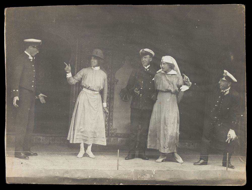 Sailors, some in drag, performing a scene on stage. Photographic postcard, 191-.