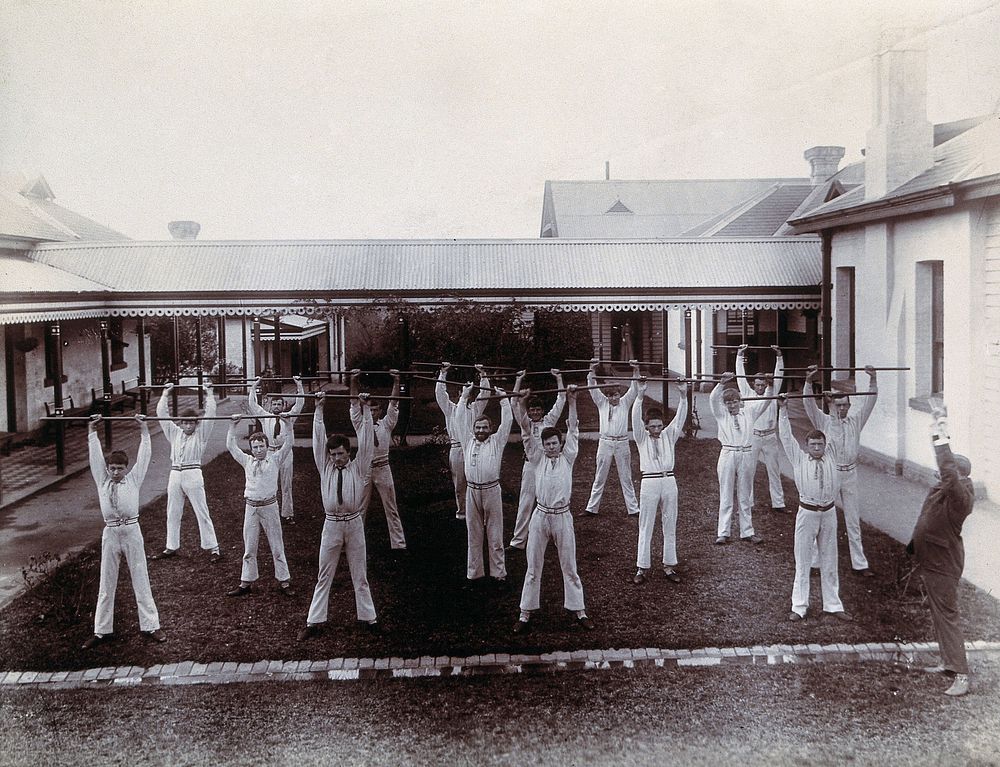 Metropolitan Lunatic Asylum, Kew, Victoria (Australia): male patients using wooden poles to exercise with. Photograph.