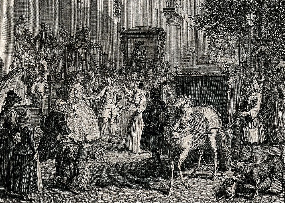 A crowd gathers and some throw confetti to cheer on a couple whose horse-drawn carriage awaits to take them to the church…