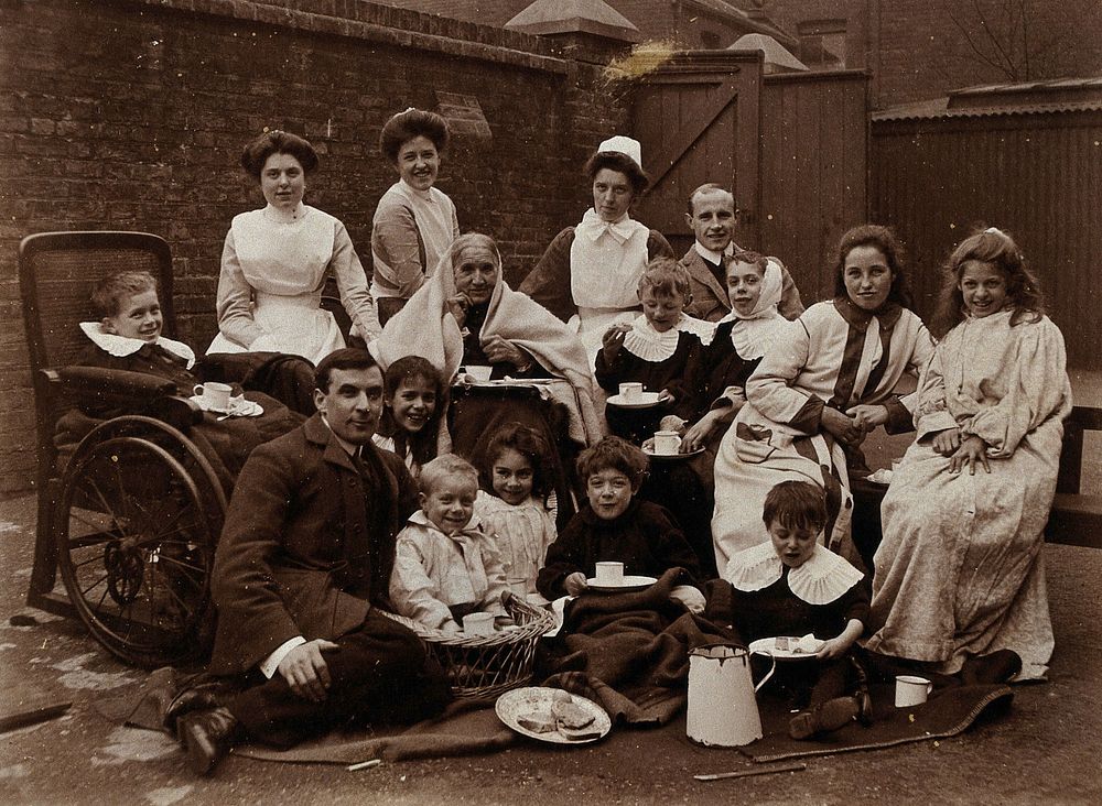 St Mary's Hospital, Plaistow: Basil Hood and Robert Archibald with patients and nurses, having tea outdoors. Photograph…