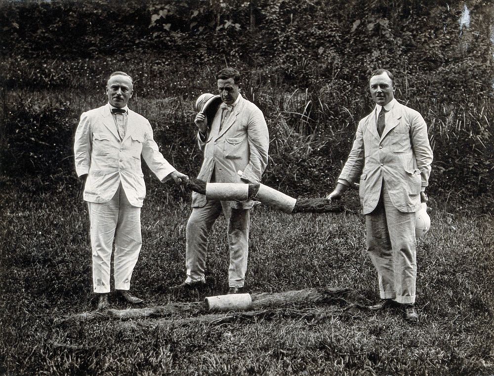 Kuala Lumpur, Malaysia: three men in pale-coloured suits holding up pipes blocked with grass roots. Photograph, 1910/1920 .