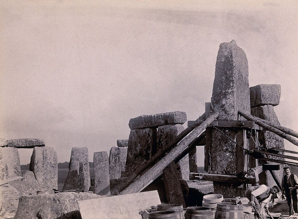 Stonehenge, England: the straightening of a leaning stone which is attached to a wooden frame and supported by beams and…