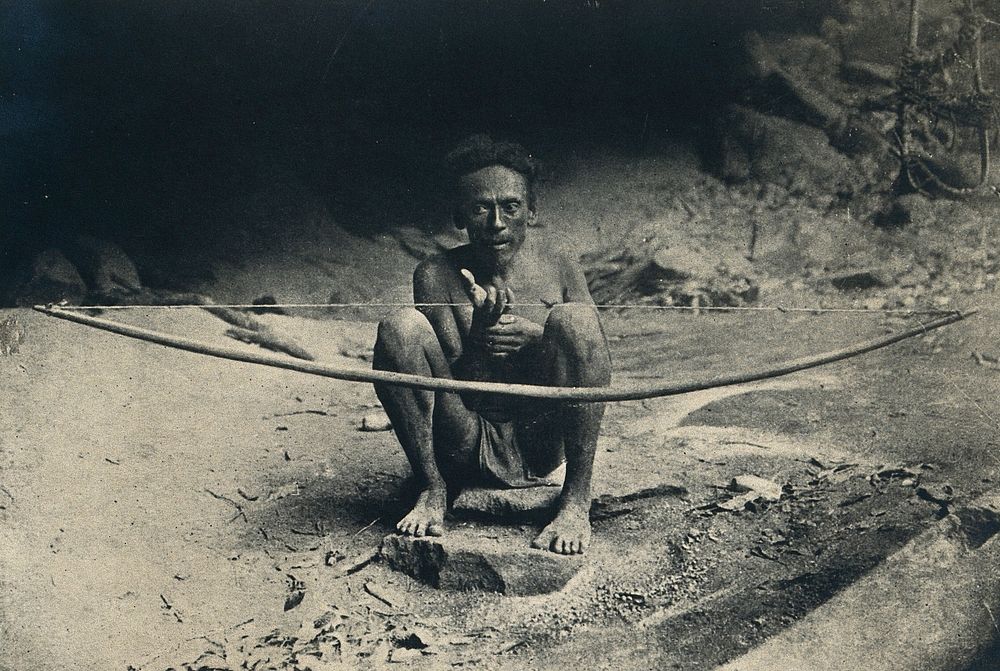 Ceylon, India: a shaman holding a large bow for a divination ritual. Process print, 1910/1930.