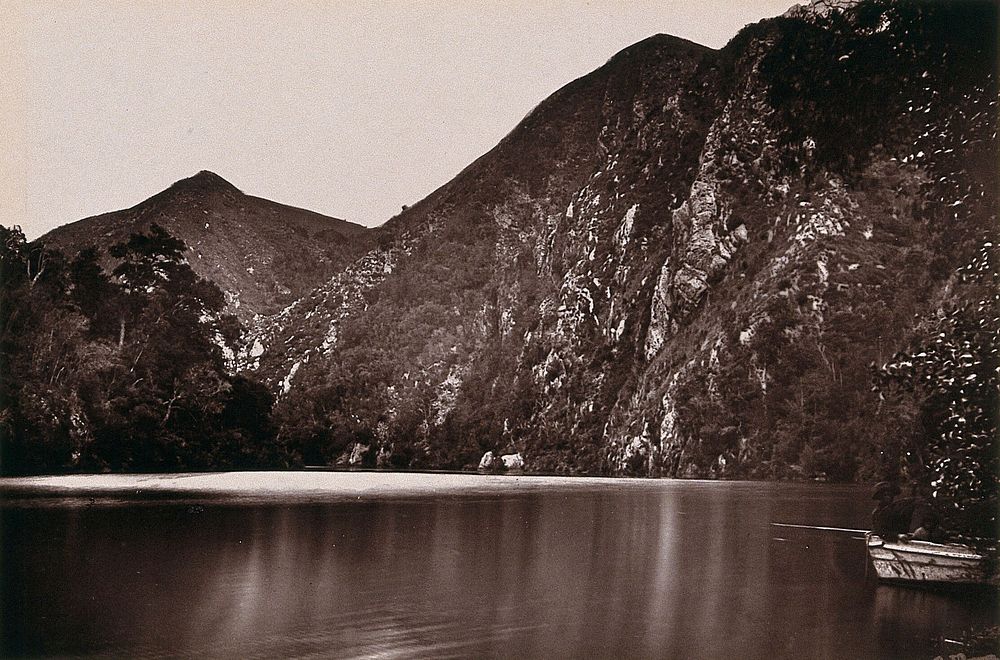 Knysna Lakes, South Africa: a lake with a boat and hills. Woodburytype, 1888, after a photograph by Robert Harris.
