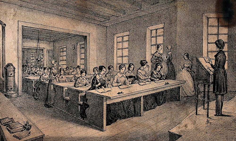 A classroom with children sitting at long tables and a teacher standing with a book in her hand. Lithograph by J.B. Sonde.