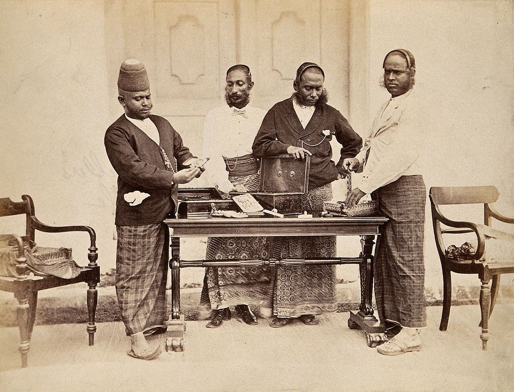 Galle, Sri Lanka: jewellers in traditional dress displaying their jewellery on a table. Photograph, ca. 1900.