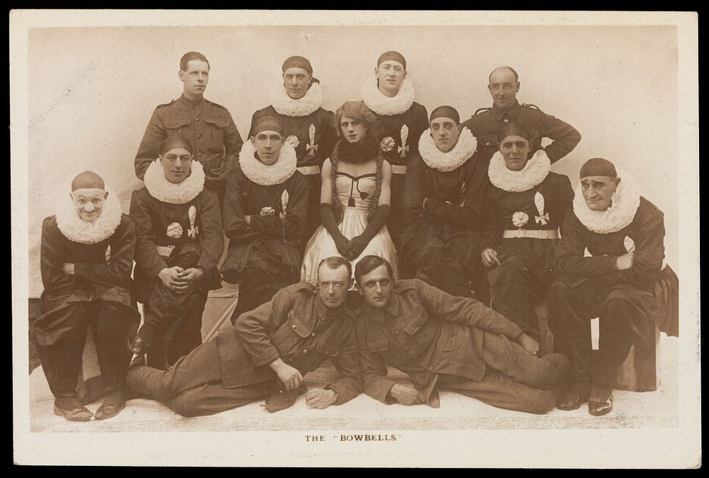 Amateur actors, one in drag, known as "The Bowbells"; posing for a group portrait. Photographic postcard, 191-.