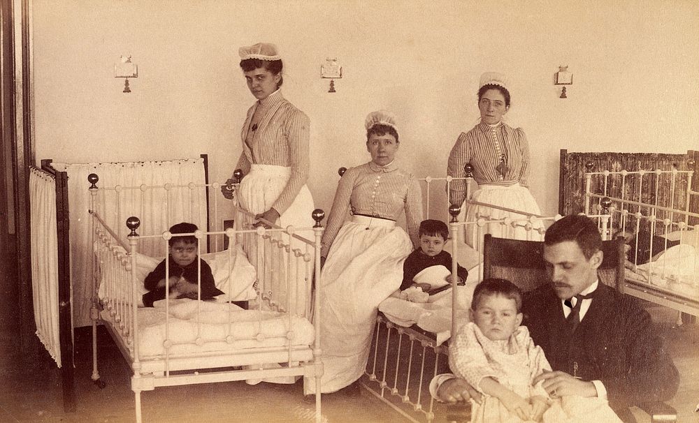 Bellevue Hospital, New York City: children in a ward with nurses and a doctor . Photograph.