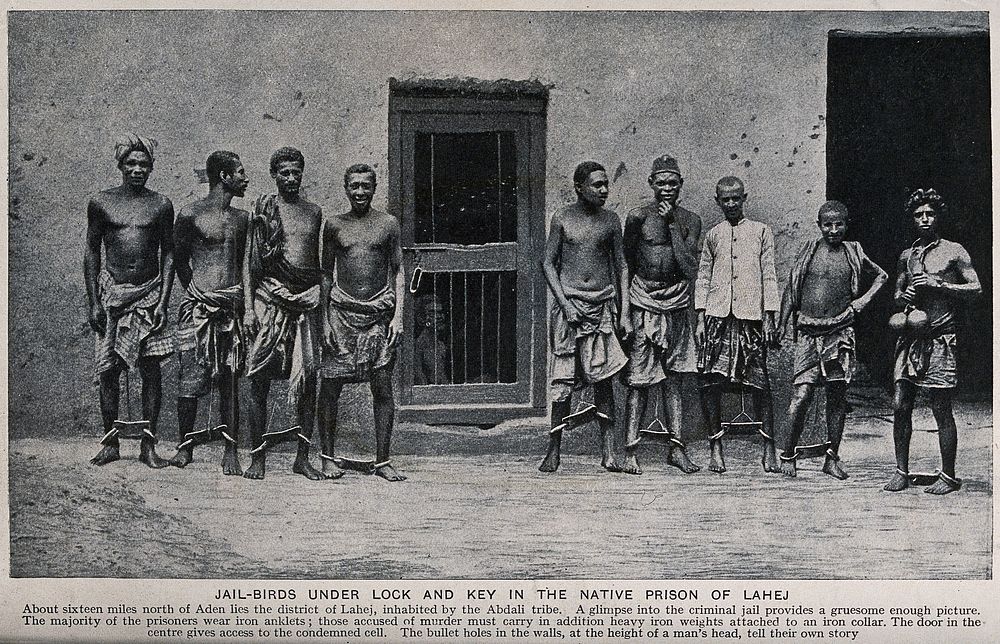 Nine male prisoners In Yemen wearing leg irons. Process print.