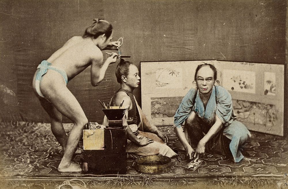 Japan: a hairdresser wearing a loin cloth at work on a kneeling man; a man in a robe squats in front of him. Coloured…