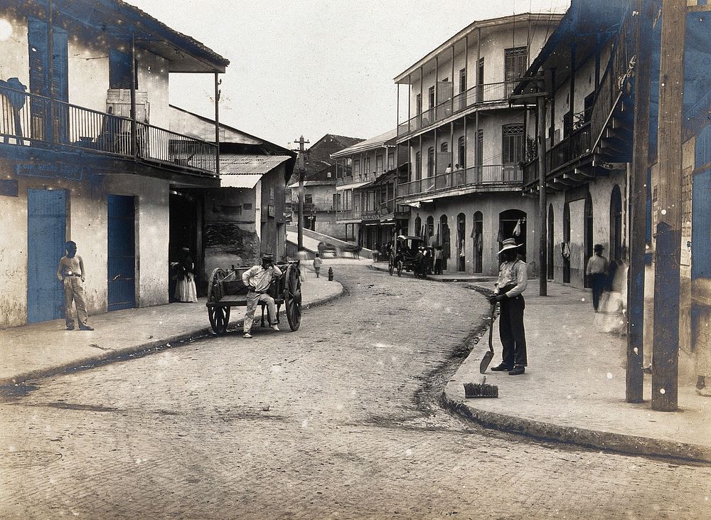 North Avenue, Panama: newly paved busy street with carriages, residents and workers; lined with large buildings with…