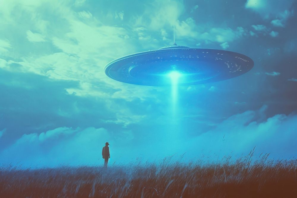 The UFO shines on a male standing on the grass outdoors nature night.