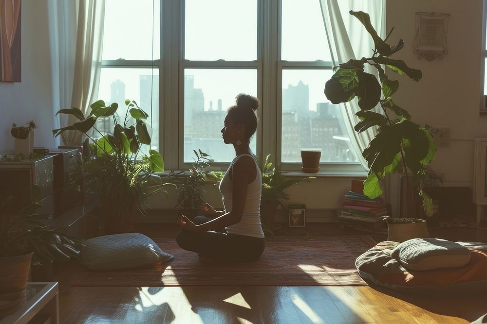 A woman poses for yoga in an apartment living room sitting adult plant.