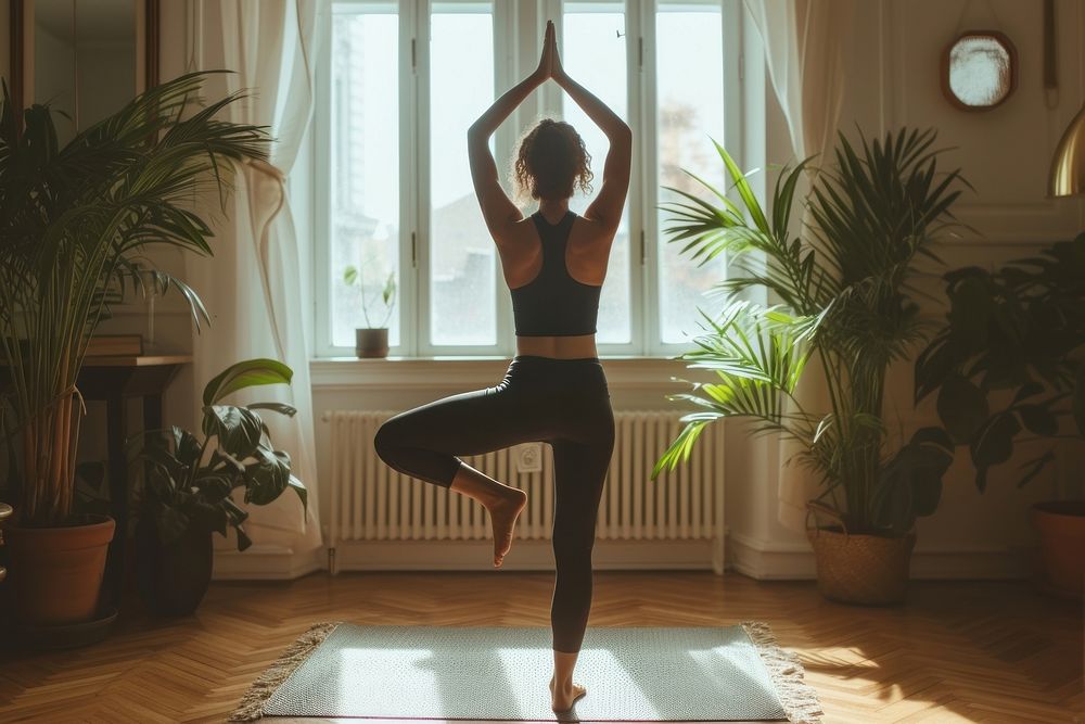 A woman poses for yoga in an apartment living room sports adult gym.