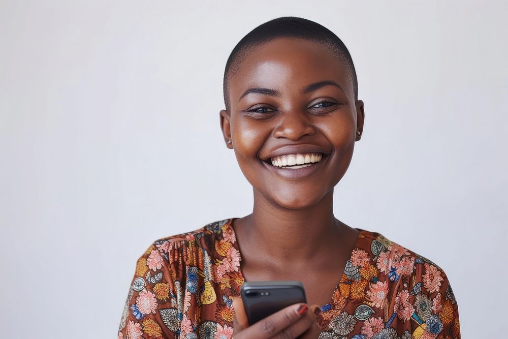 African woman with short haircut holding cellphone smiling adult smile.