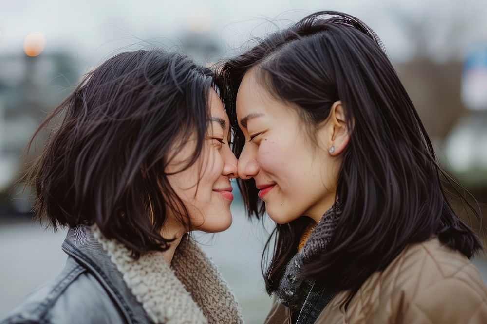 Older asian lesbian couple kiss portrait affectionate togetherness.