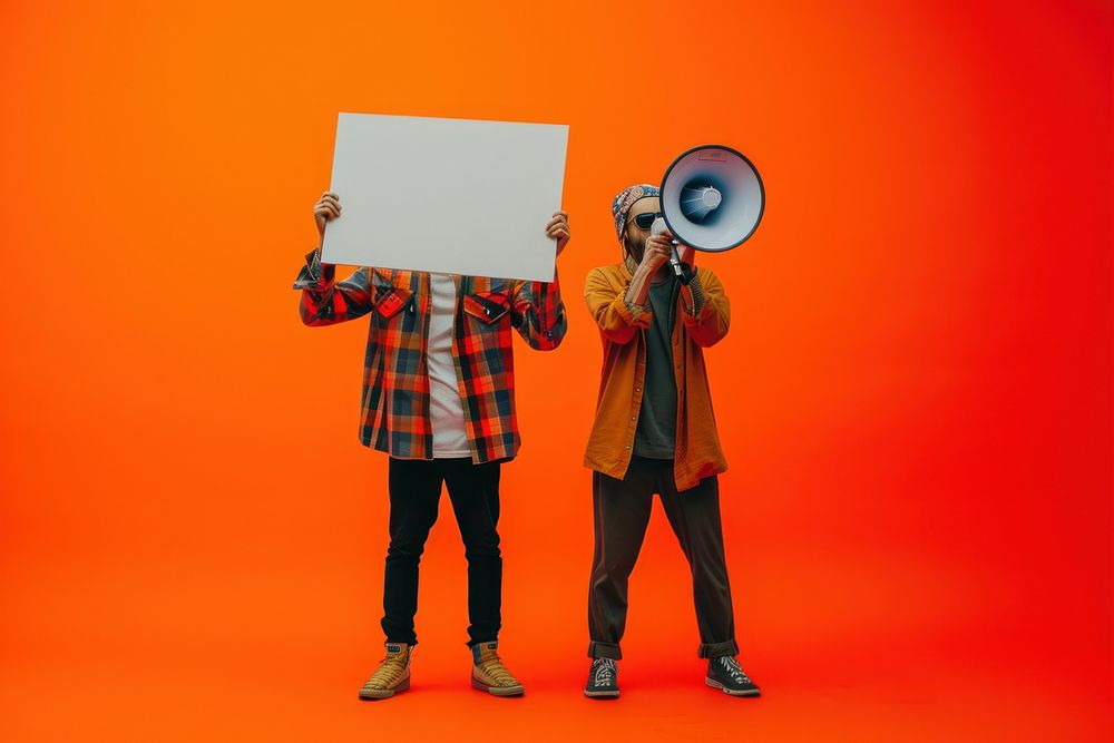 Two people holding megaphones while holding large signs on an orange background photography adult togetherness.