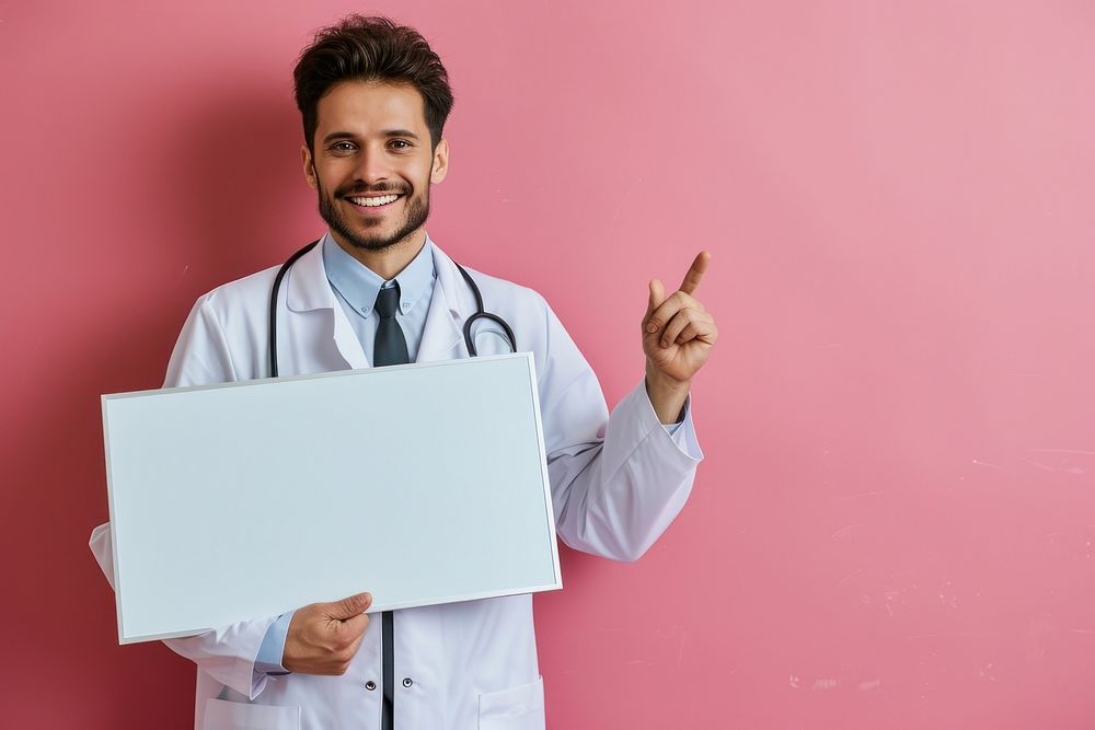 A smiling male doctor is pointing at floating in air mini white board adult stethoscope accessories.